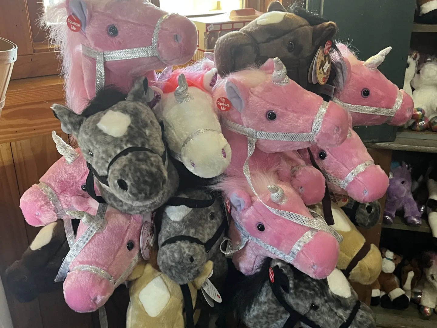 A display of plush horse and unicorn stick toys in various colors.