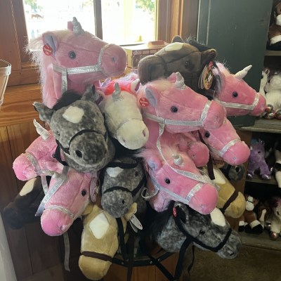 A display of plush horse and unicorn stick toys in various colors.