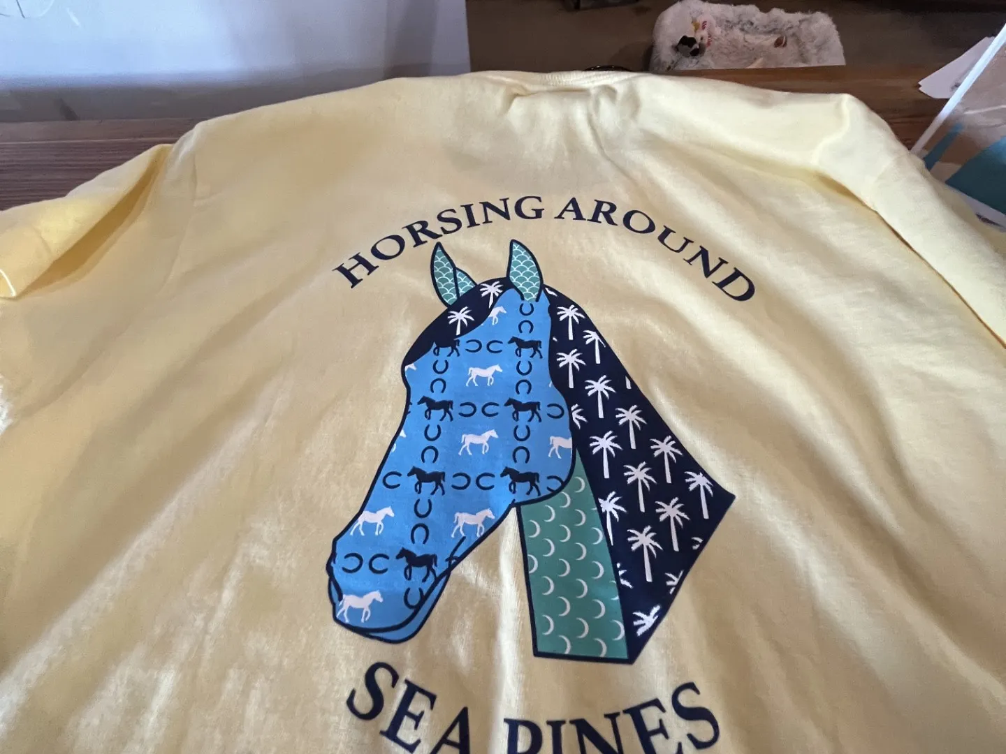 Yellow shirt with horse graphic and text 'Horsing Around Sea Pines'.