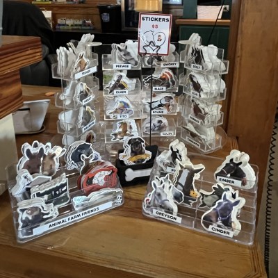 Display of animal stickers on a counter with names and prices.